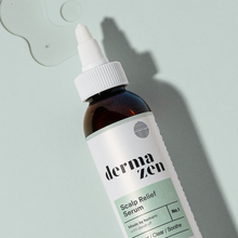 Bottle of Dermazen Scalp Relief Serum on a light background with drops of the serum beside it.